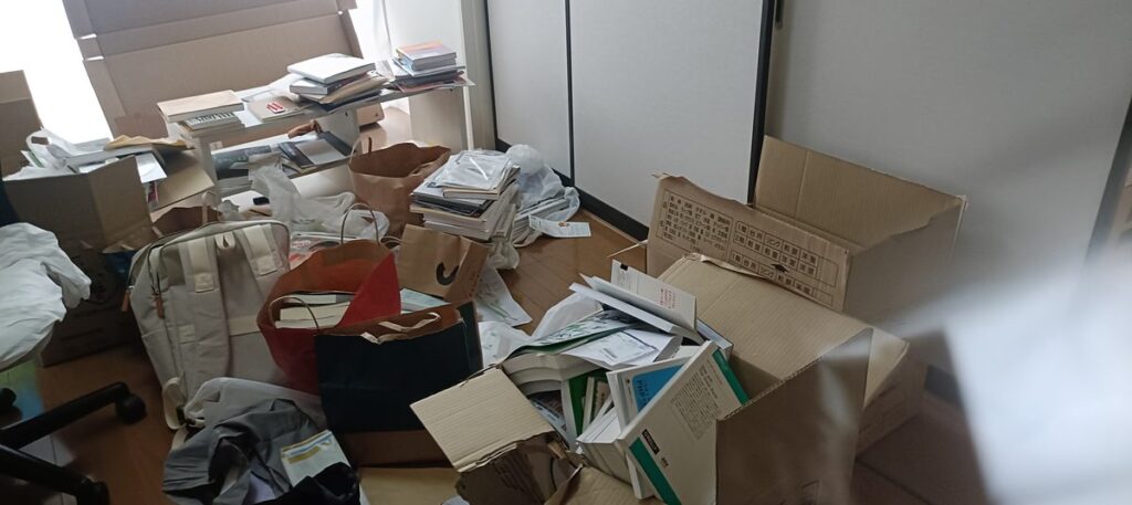 机のまわりに書類と段ボールが散らばった状態