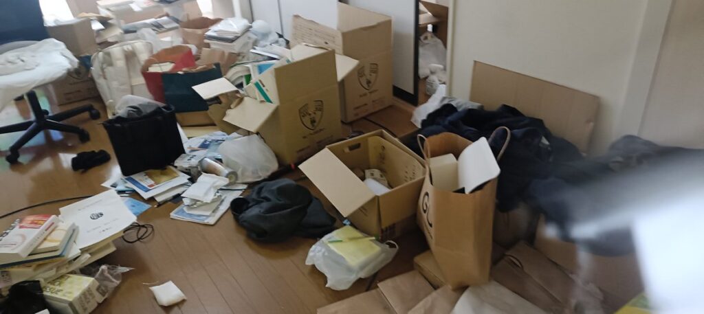 床一面に書類と紙袋が広がった部屋